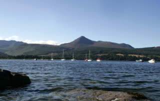 Boats in water in front of mountain